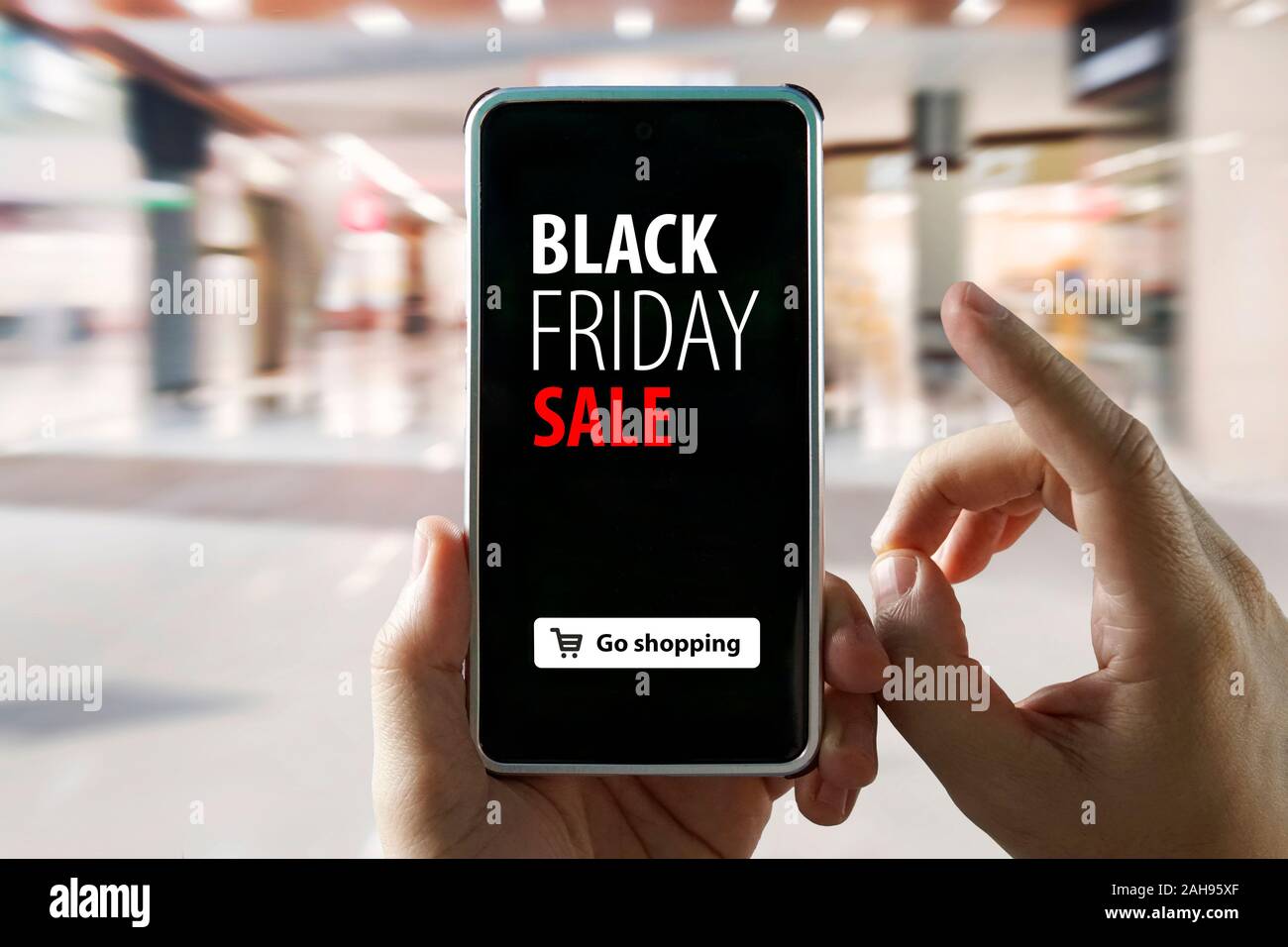 Hände halten Handy mit schwarzer Freitag Verkauf auf dem Bildschirm auf verschwommenes Bild der Shopping Mall. Kauf von Waren über das Internet in die mobile Anw Stockfoto
