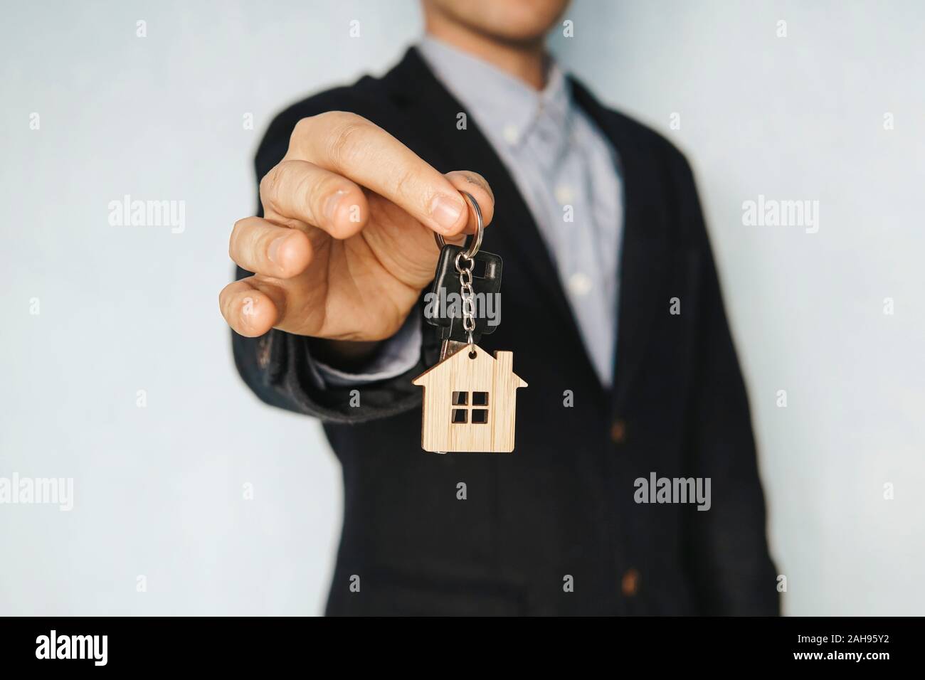 Haus heraus halten, die Schlüssel auf einem Haus geformte Schlüsselbund. Konzept des Verkaufs von Immobilien. Die Vermietung einer Ferienwohnung. Ein Zimmer mieten. Stockfoto