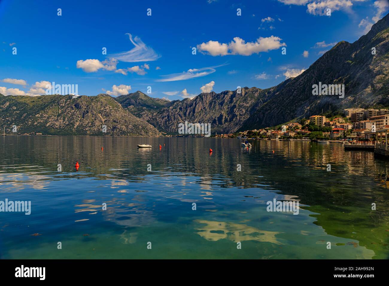 Alte Steinhäuser in der Bucht von Kotor oder Boka Kotorska und die umliegenden Berge mit kristallklarem Wasser auf dem Balkan, in Montenegro an der Adria Stockfoto