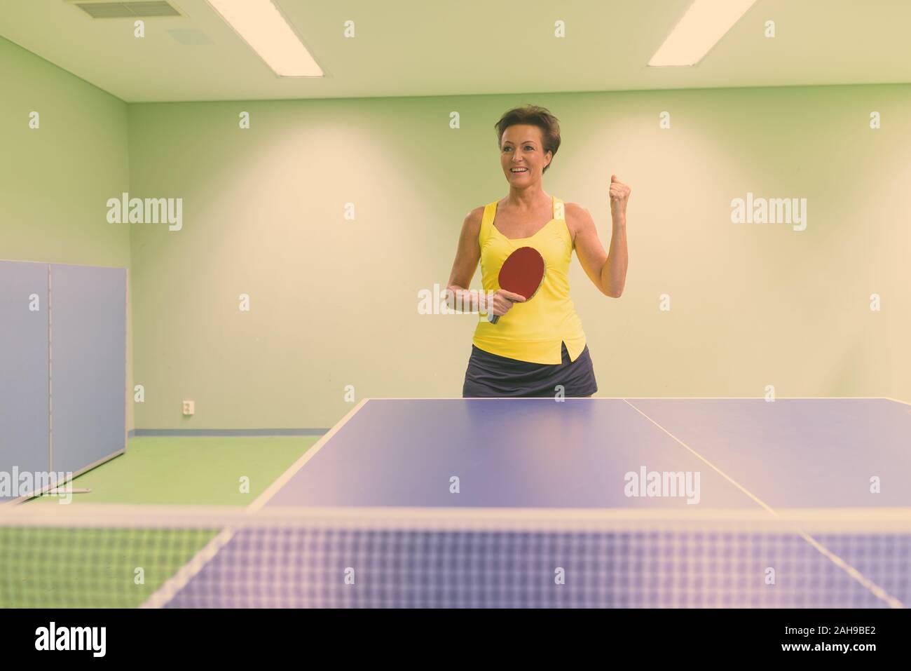 Reife Frau, schön spielen Tischtennis im Innenbereich Stockfoto