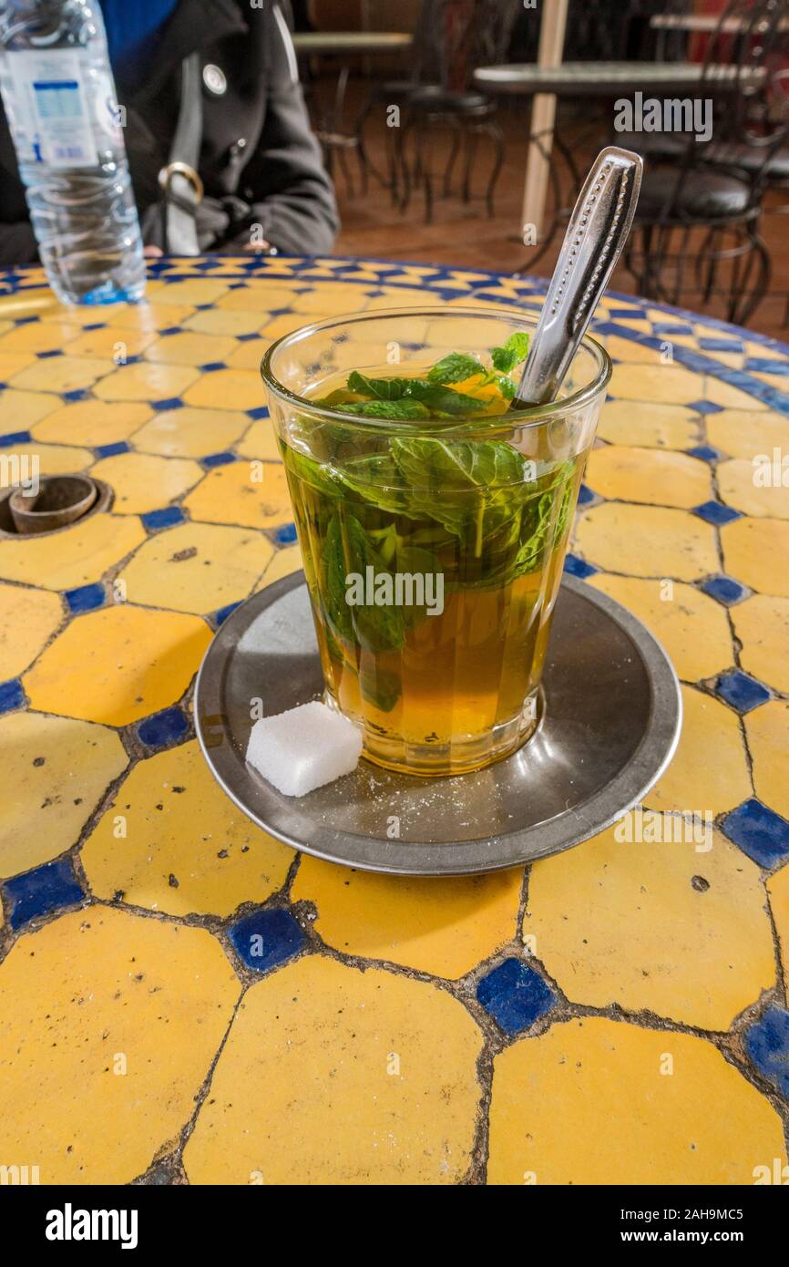 Traditionelle Glas mit Pfefferminztee auf einem Fliesen- Tabelle. Medina, Marrakesch, Marokko Stockfoto