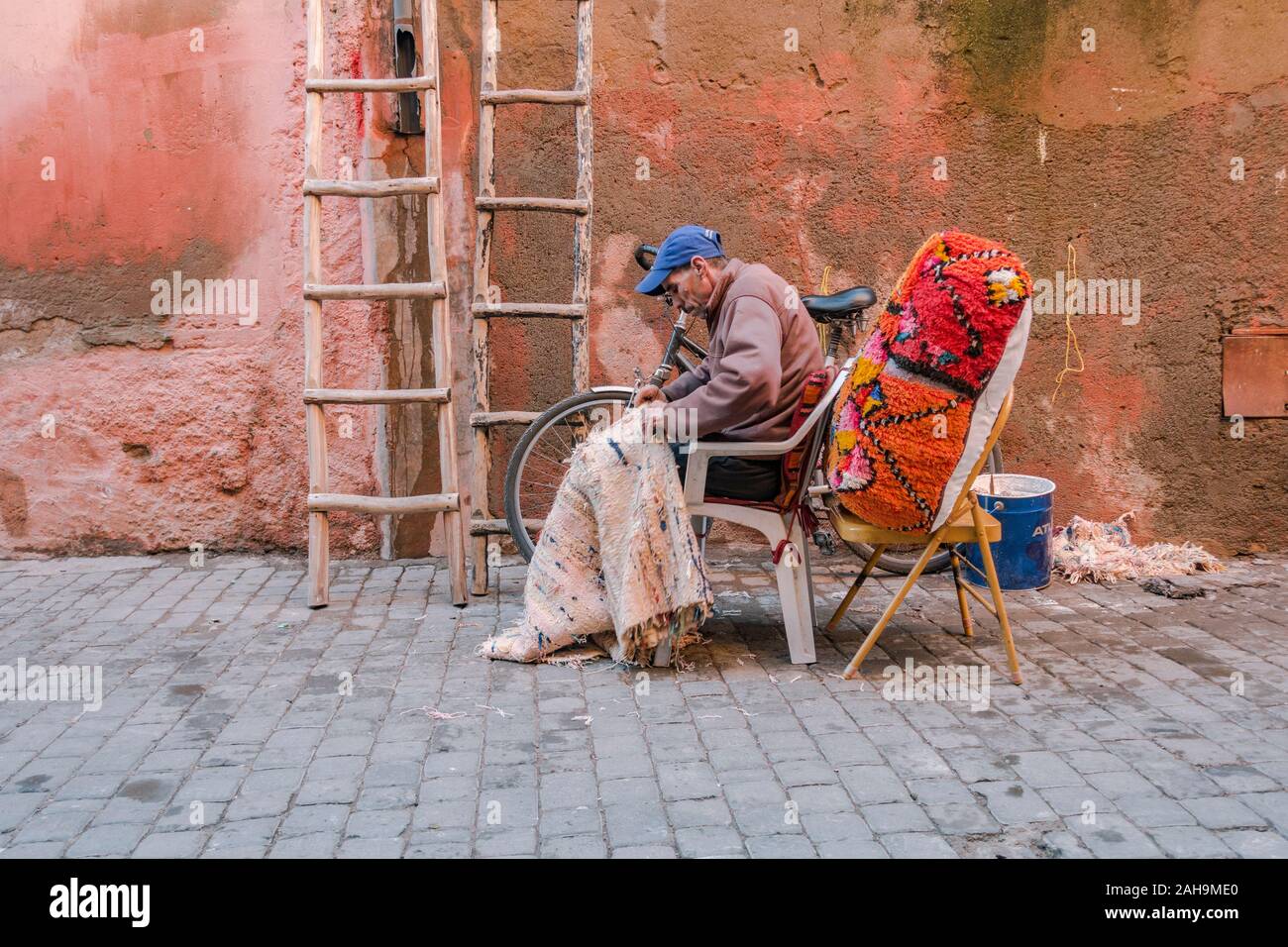 Mann auf einem marokkanischen Teppich in den Gassen der alten Medina von Marrakesch, Marokko. Stockfoto