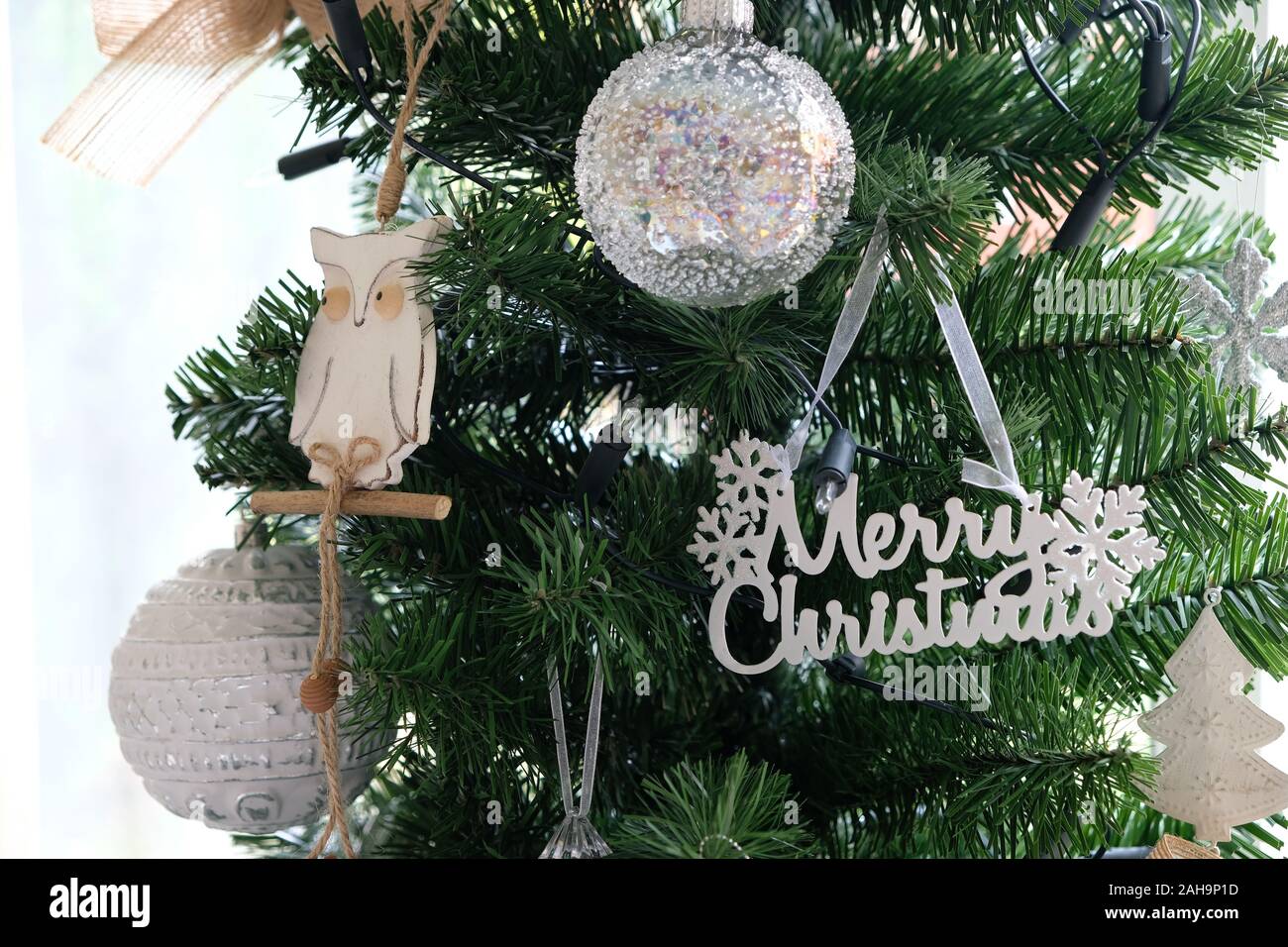 Dezember 2019 - Weiß und Silber Weihnachtsschmuck hängen auf einer traditionellen, künstlichen grünen Weihnachtsbaum Stockfoto
