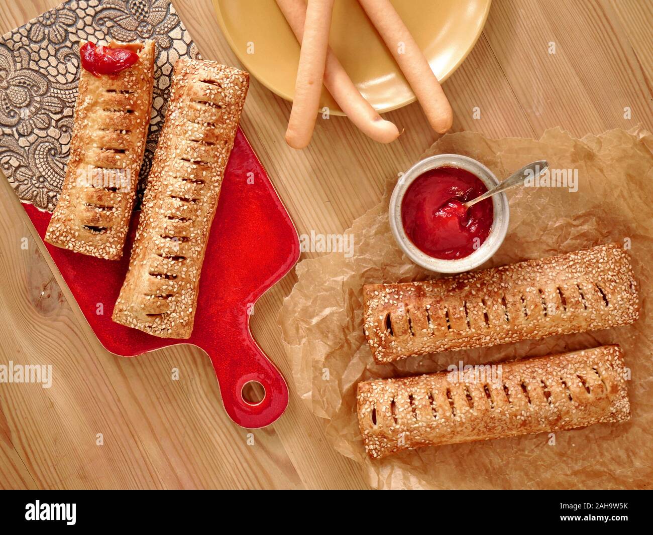 Hausgemachte mini Hot Dogs mit Wurst, Sesamsamen und frischer Tomatensauce. Stockfoto