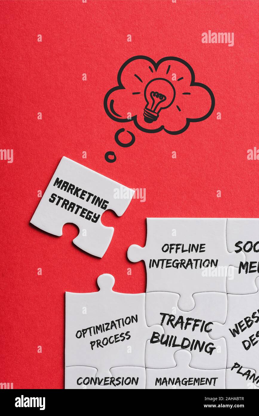 Blick von oben auf die unvollendete weiß Rätsel in der Nähe von Blatt mit Marketing Strategie Schrift auf Rot Stockfoto