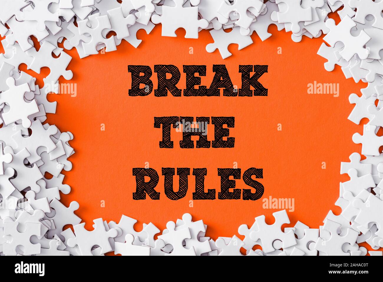 Blick von oben auf die Rahmen der weißen Puzzle Stücke um brechen die Regeln Schriftzug auf Orange Stockfoto