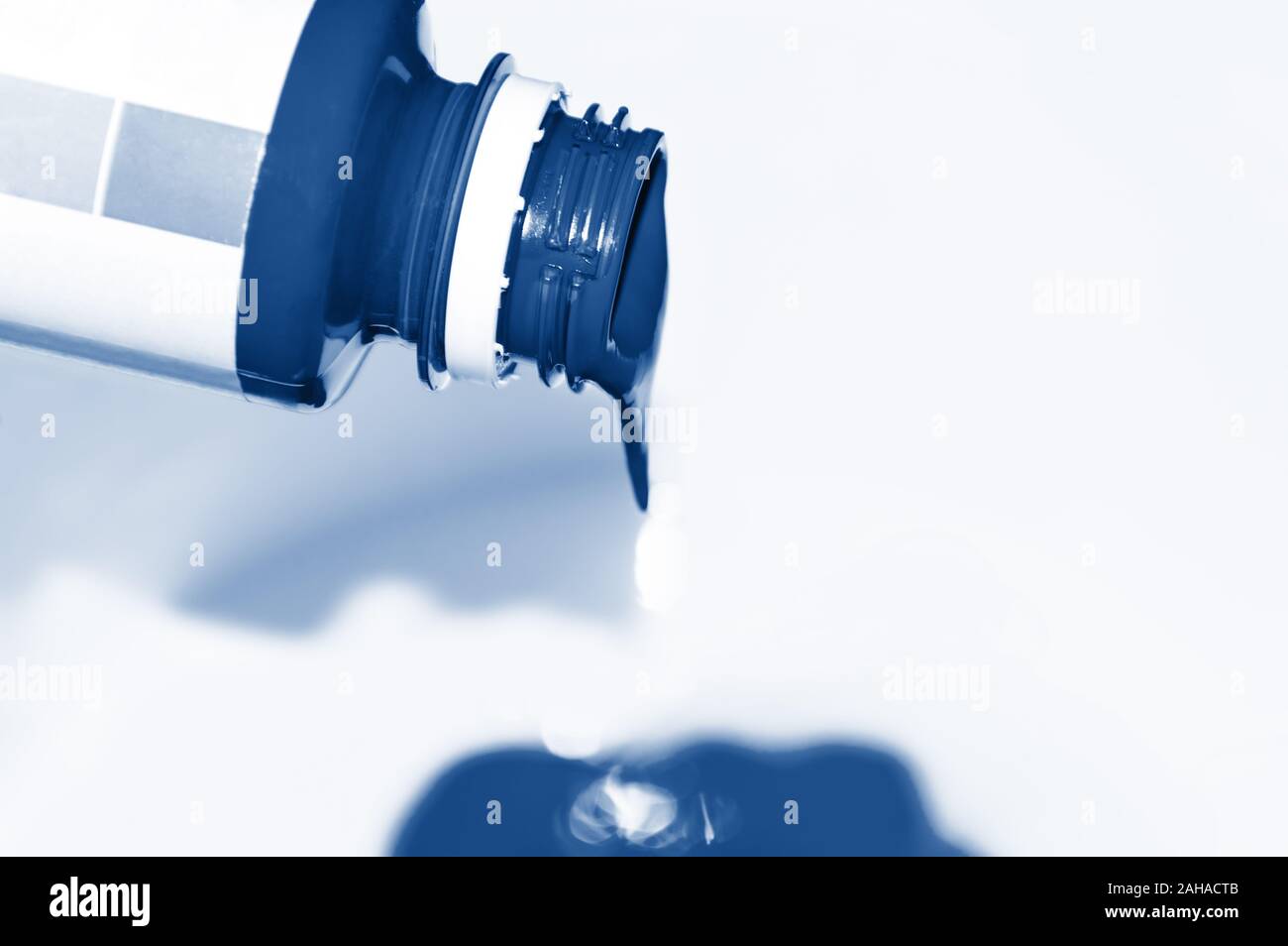 Einen Tropfen classic Blau Lack fallen aus der Flasche auf weißem Hintergrund. Trendfarbe des Jahres 2020 Konzept Stockfoto