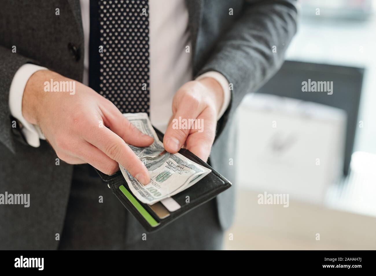 Die Hände der Reichen elegante Geschäftsmann in Anzug holding Brieftasche und Dollar Banknoten Stockfoto