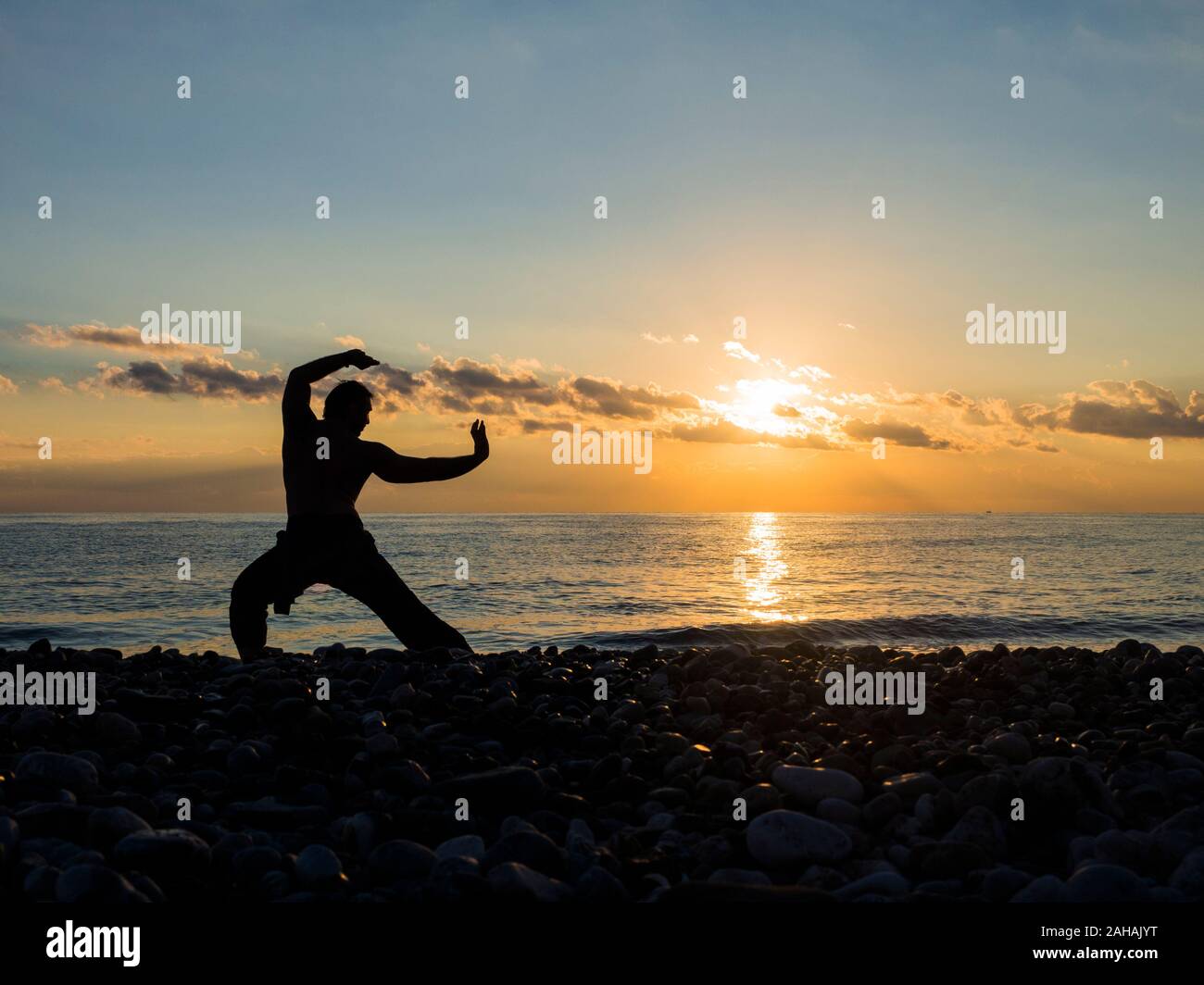 Martial Artist mit orange Sonnenuntergang. Silhouette eines Mannes der Praxis whushu. Gesunde Lebensweise. Stockfoto