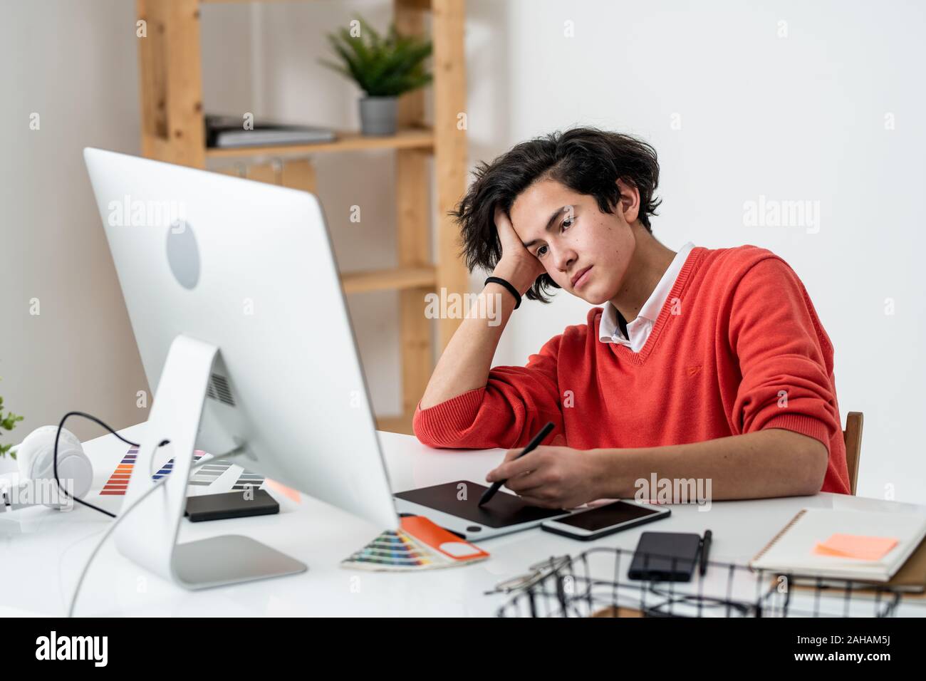 Müde männliche Freelancer suchen Bei computer Bildschirm beim Retuschieren Fotos vom Schreibtisch Stockfoto