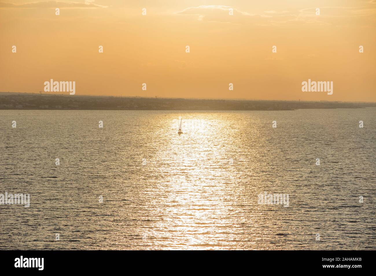 Segeln Bei Sonnenuntergang. Saisonale Bilder mit glänzendem Meer und segelboot über bewölktem Himmel und Sonne bei Sonnenuntergang Apulien Küste, Italien. Stockfoto