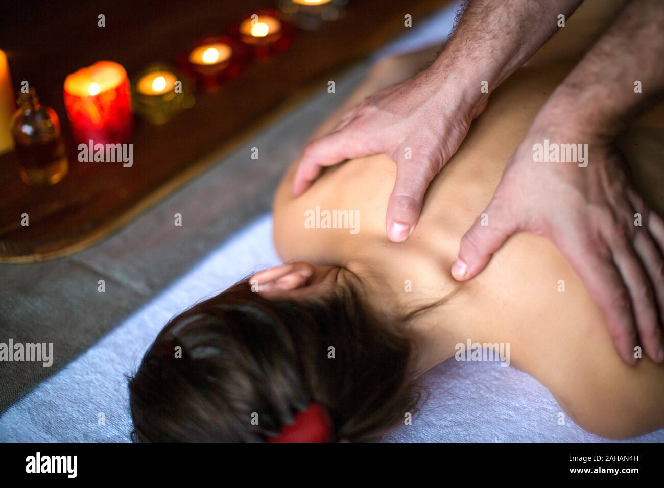Männer Hände machen eine therapeutische Massage für ein Mädchen auf einer Massageliege in einer Massage Spa mit dunklen Beleuchtung liegen. Gesundheit, Wellness, und anhand von quantitativen Simulatio entspannen Stockfoto