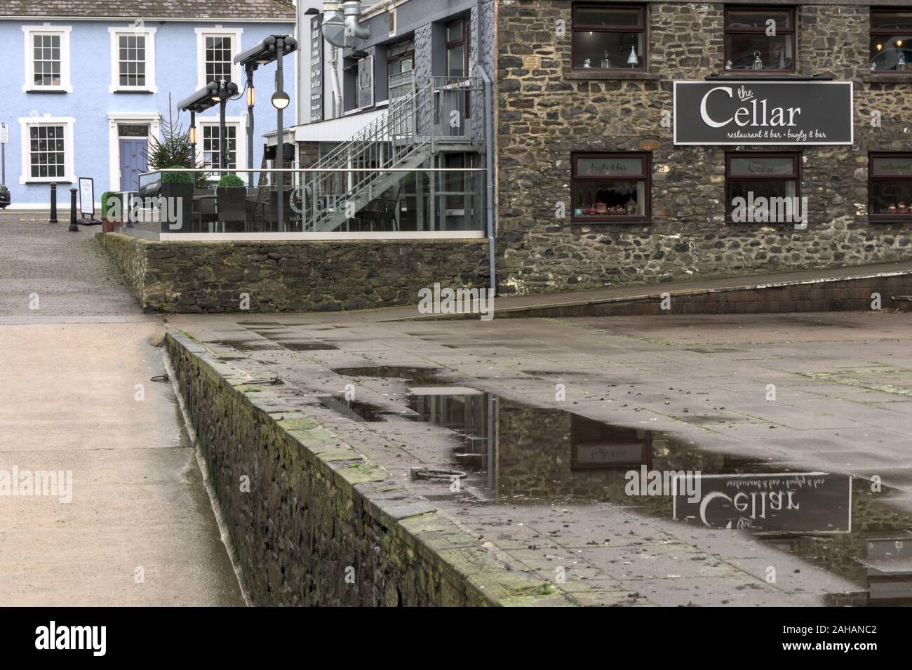 Aberaeron Ceredigion Wales UK 27 Dezember 2019: Die Kellerbar, Aberaeron und Reflexion von Schildern in der Pfütze Stockfoto