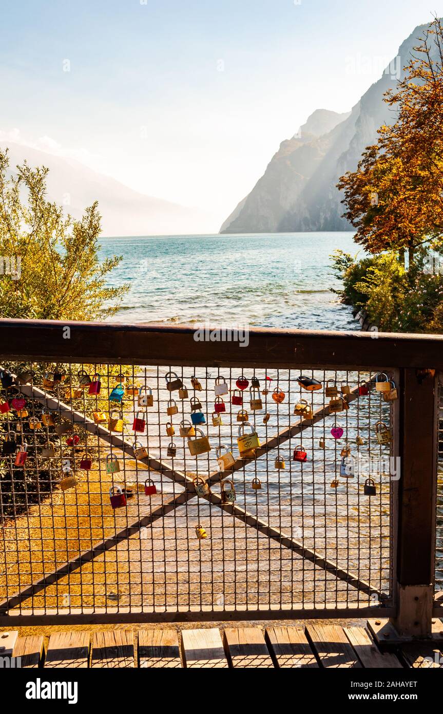 Riva del Garda, Lombardei, Italien - 12 September 2019: Liebe und Ehe Schlösser hängen auf Metallgitter auf hölzernen Geländer in Riva del Garda Stadt mit Bea Stockfoto