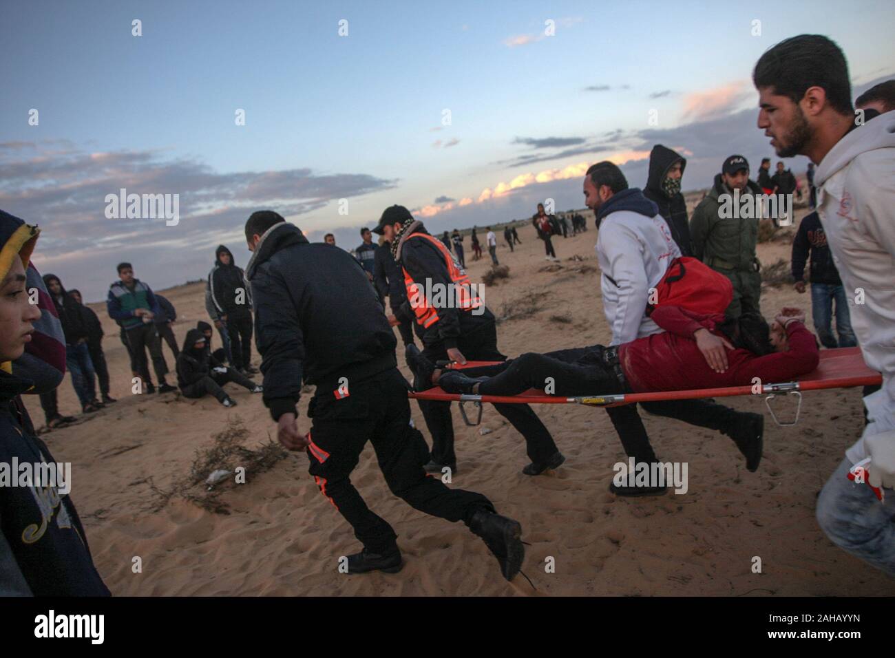 Rafah, Gaza. 27 Dez, 2019. Palästinensische Sanitäter weg ein verletzter Demonstrant bei Auseinandersetzungen nach einer Demonstration an der Grenze zu Israel östlich von Rafah im südlichen Gazastreifen. am Freitag, den 27. Dezember 2019. Palästinenser im Gazastreifen wieder Proteste entlang der befestigten Grenze mit Israel Skala, Factions im Streifen am Donnerstag gesagt, Foto von Ismael Mohamad/UPI Quelle: UPI/Alamy leben Nachrichten Stockfoto