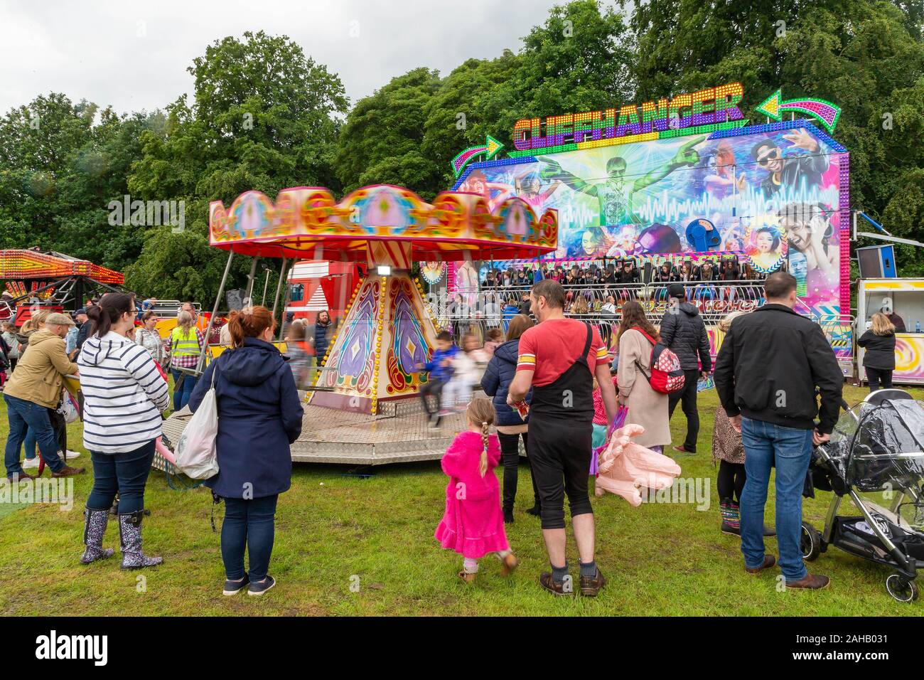 Übergeordnete Uhren Kinder auf einer Schaukel Stühle Fahrt in einem Land fair nach dem thelwall Rose Queen Prozession 2019 Stockfoto