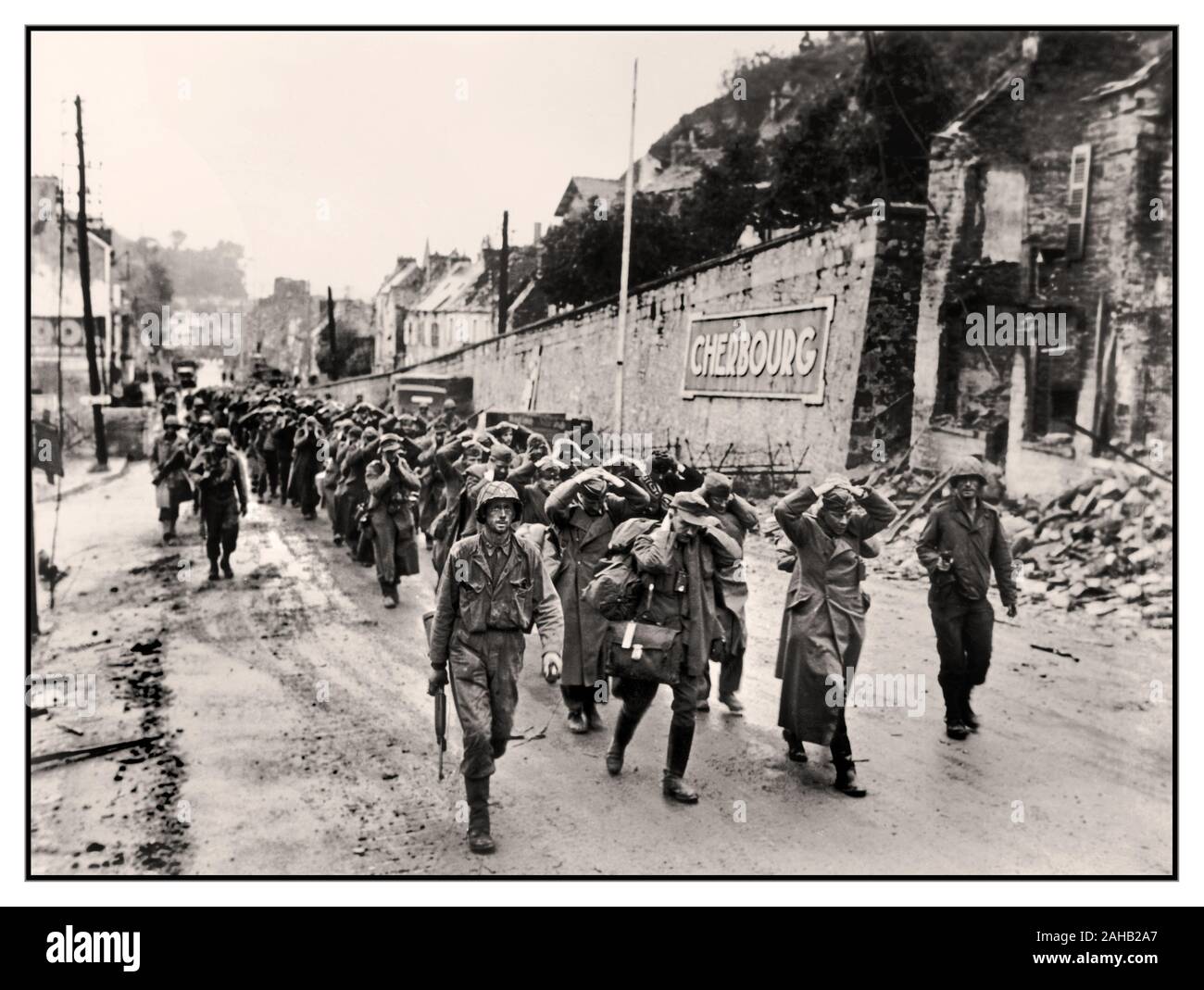 2. Weltkrieg 1944. Juni deutsche Wehrmachtgefangene nahmen und übergaben Soldaten mit Händen an Köpfen nach der Operation Overlord D-Day Offensive, die mit amerikanischen alliierten Truppen durch eine Straße in Cherbourg marschierte, WW2. Weltkrieg Frankreich Deutschland kapitulierte Hände an Köpfen Stockfoto