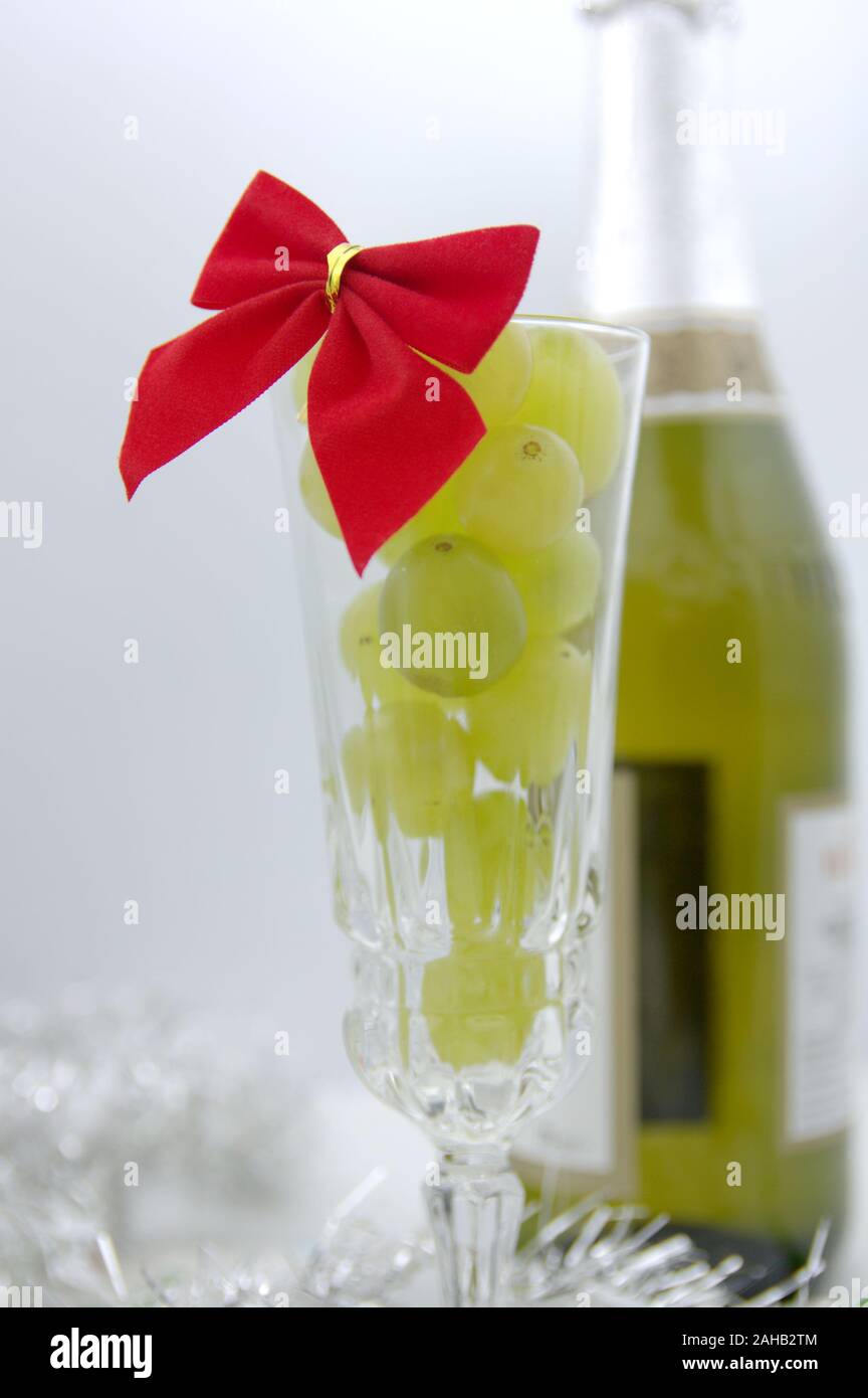 Ein Glas voller Glück Trauben, im Hintergrund eine Flasche Sekt zum Ende des Jahres zu feiern und den Beginn einer besseren Stockfoto