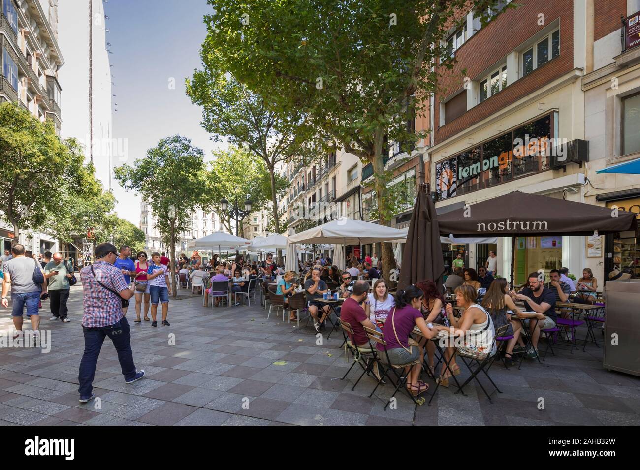 Menschen unter großen Sonnenschirmen in einem Straßencafé sitzen in Madrid, Spanien Stockfoto