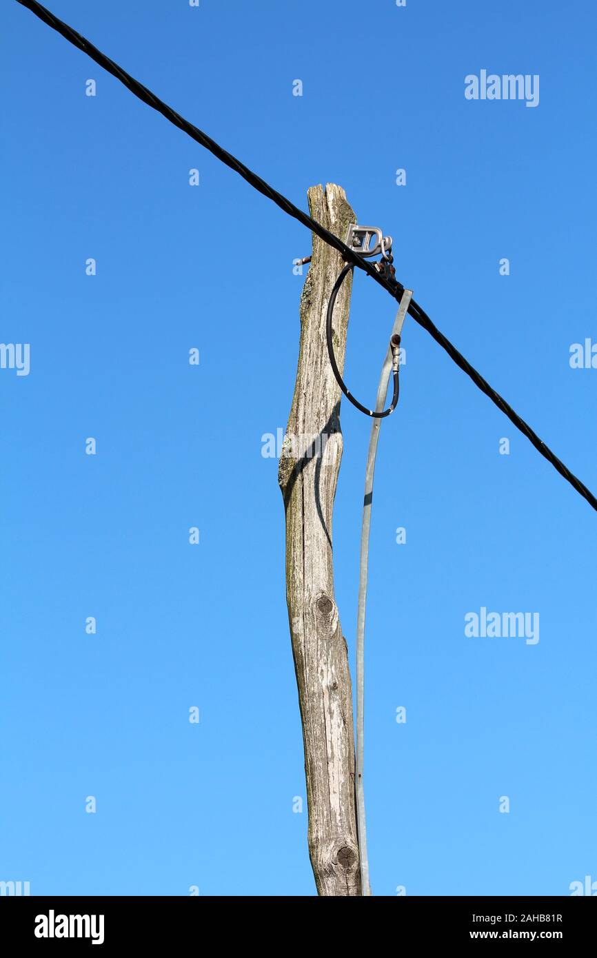 Alten krummen Holz- elektrische Gebrauchspfosten mit dicken elektrische Kabel an den klaren, blauen Himmel Hintergrund verbunden Stockfoto