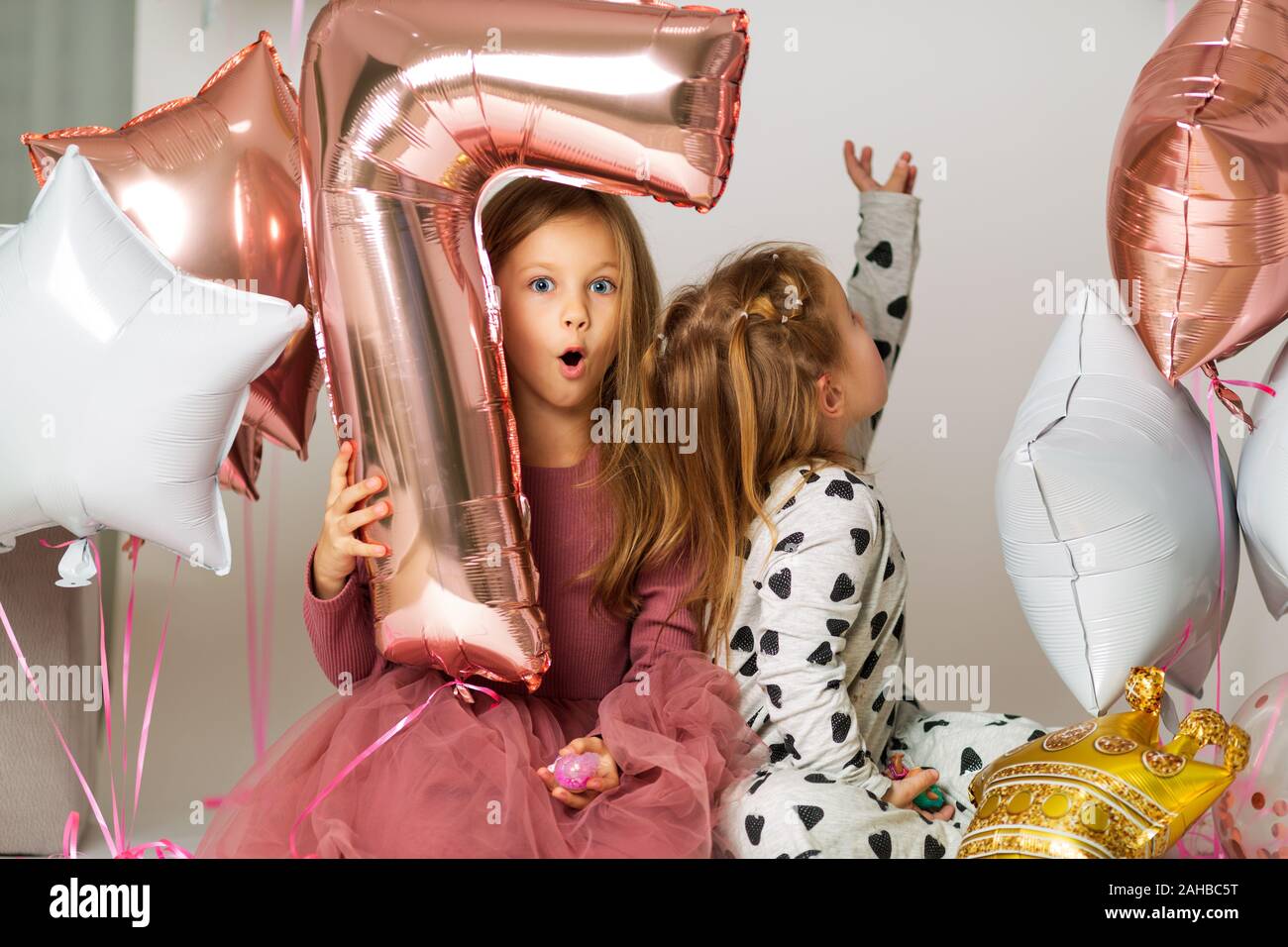 Porträt von zwei Schwestern, 7-jährige Blondine und 3-jährige Kind, Schwestern spielen mit Ballons, Ball Nummer sieben Stockfoto