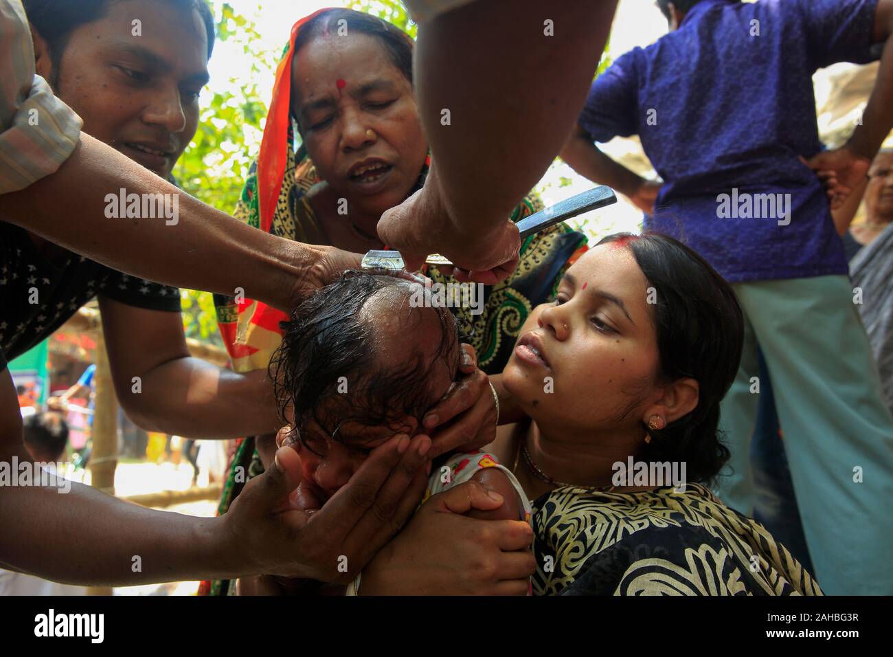 Mutter und Vater aufpassen der Friseur Scherkopf ihrer Tochter während der Bou Mela. Narayanganj, Bangladesch Stockfoto