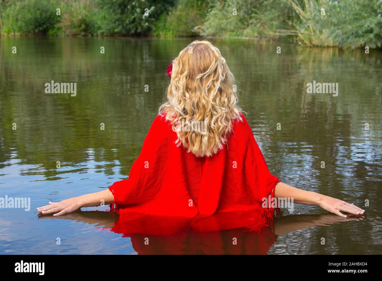Junge blonde Frau in Rot wrap Wandern im natürlichen Wasser Stockfoto