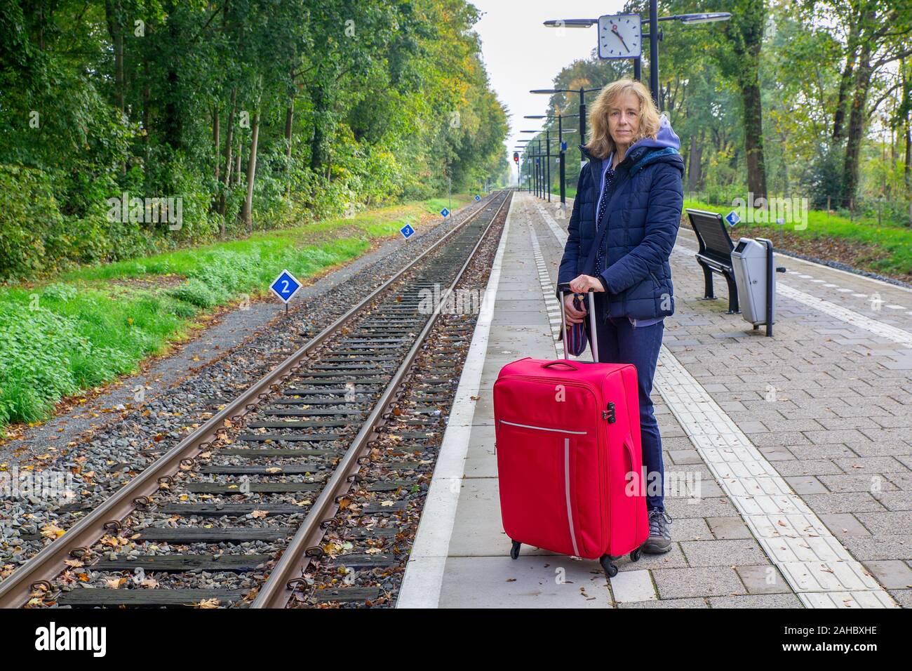 Kaukasische Frau mit roten Koffer stehen am Bahnhof Stockfoto