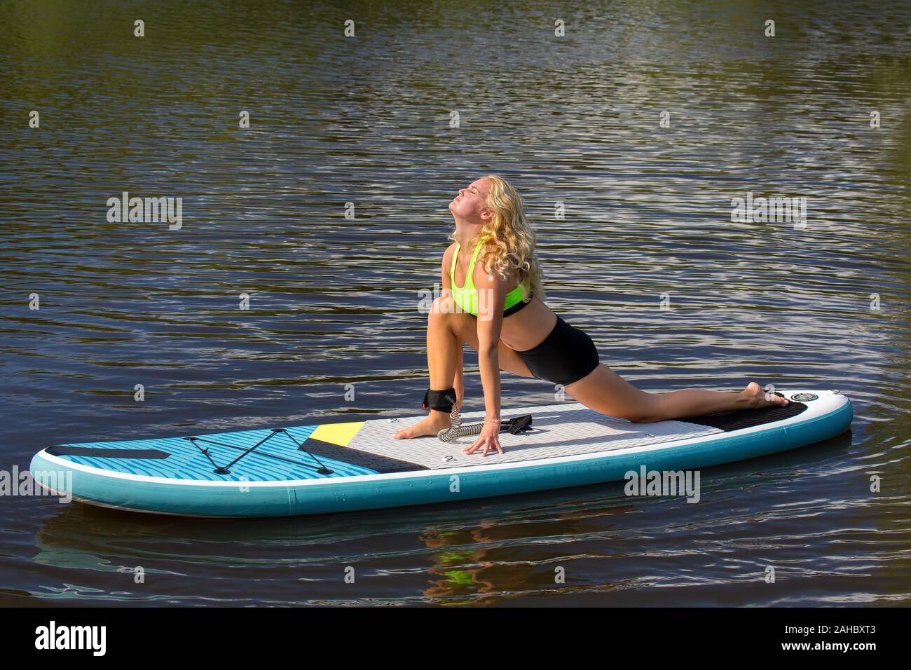 Junge blonde Holländerin erstreckt sich auf SUP am Wasser Stockfoto