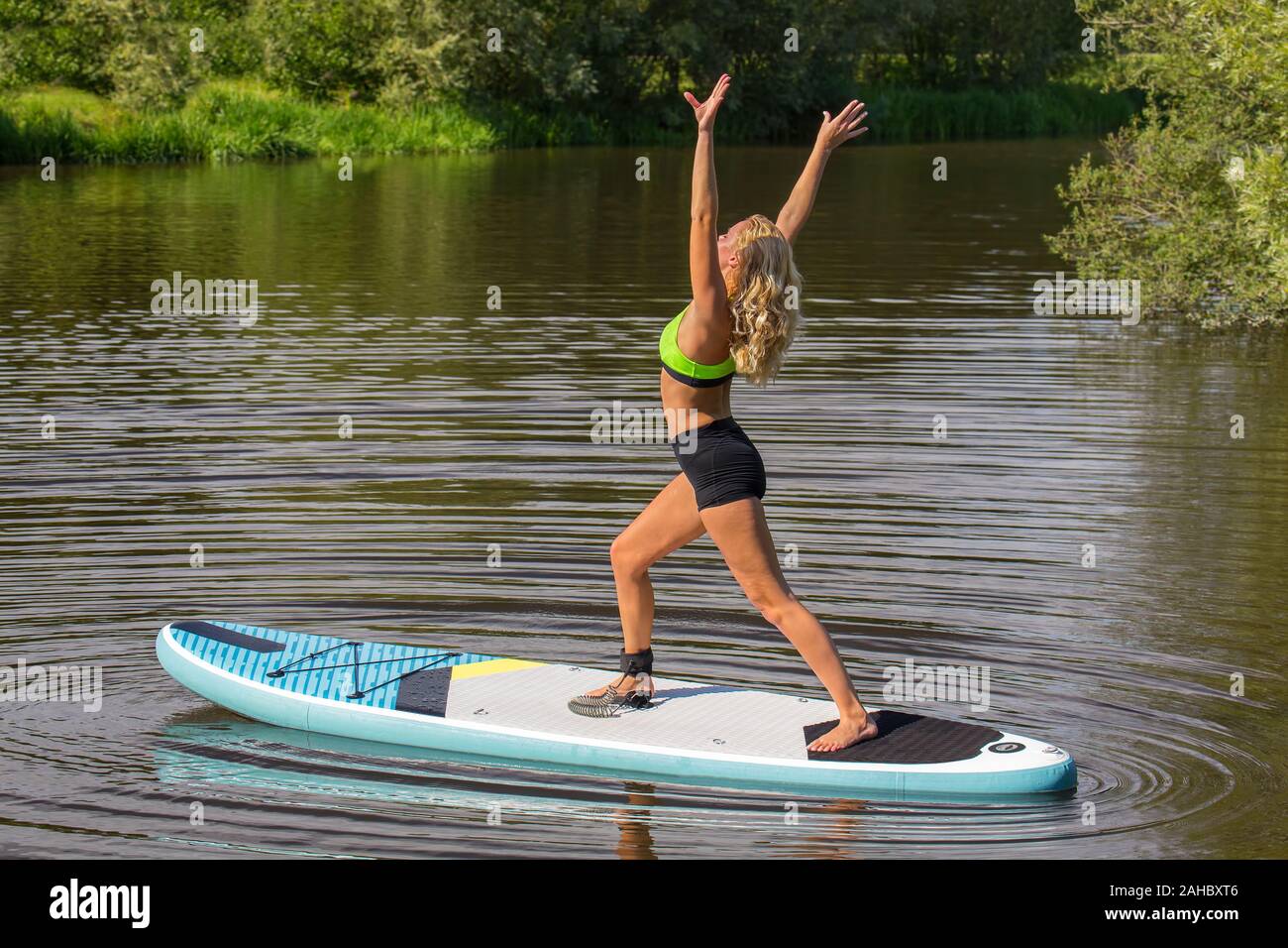 Ständigen jungen kaukasischen Frau auf SUP im Yoga Pose auf dem Wasser Stockfoto