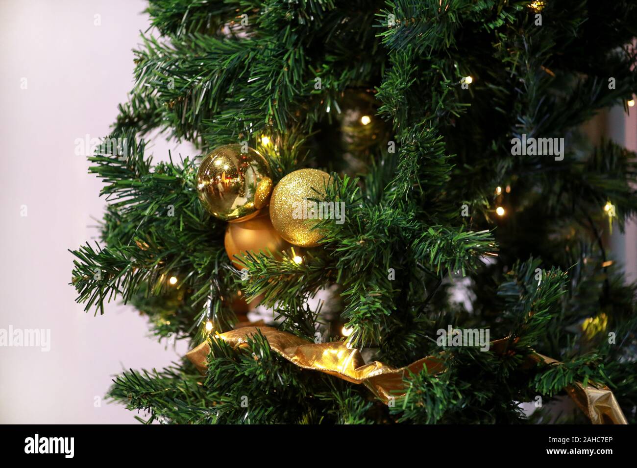 Traditionell dekorierte Christbaumkugeln hängt an grüne Zweige Baum der Kiefer. Helles gold Kugeln am Weihnachtsbaum Tanne oder mit string Reis Glühlampen Fichte. Stockfoto