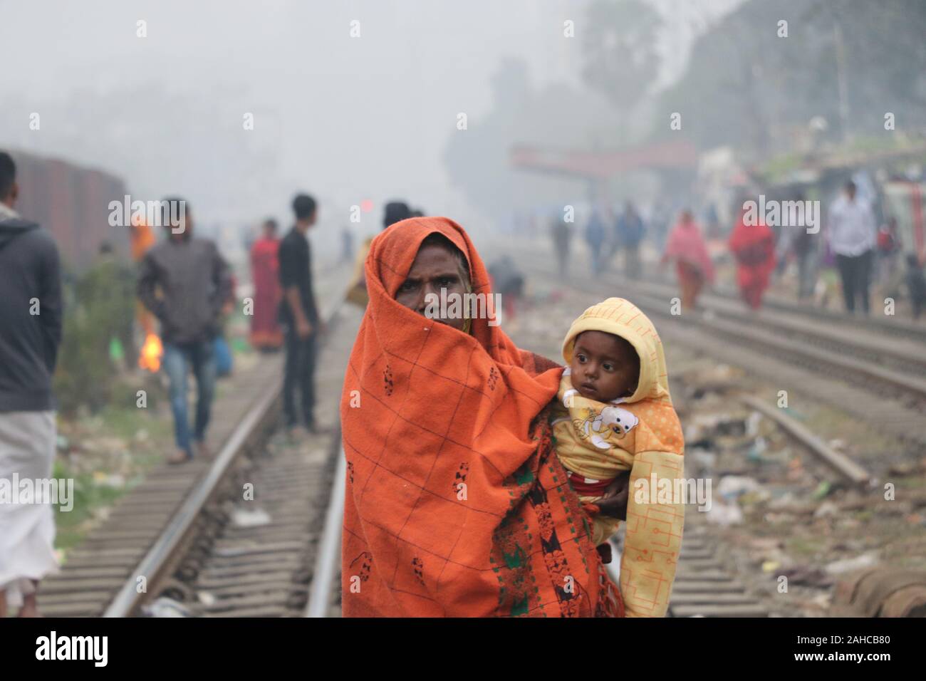 Winter kalt tejgoanischer Bahnhof, 21de2019 tejgoanischer BahnhofDhaka Bangladesh.eine ältere Frau hält das Baby in ihren Armen und wickelt es mit einem Laken um es vor der Kälte zu schützen.Nazmul Islam/alamy Stock Live News Stockfoto