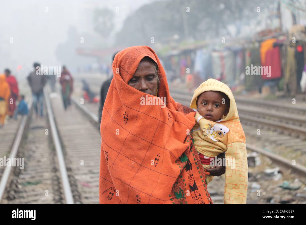 Winter kalt tejgoanischer Bahnhof, 21de2019 tejgoanischer BahnhofDhaka Bangladesh.eine ältere Frau hält das Baby in ihren Armen und wickelt es mit einem Laken um es vor der Kälte zu schützen.Nazmul Islam/alamy Stock Live News Stockfoto