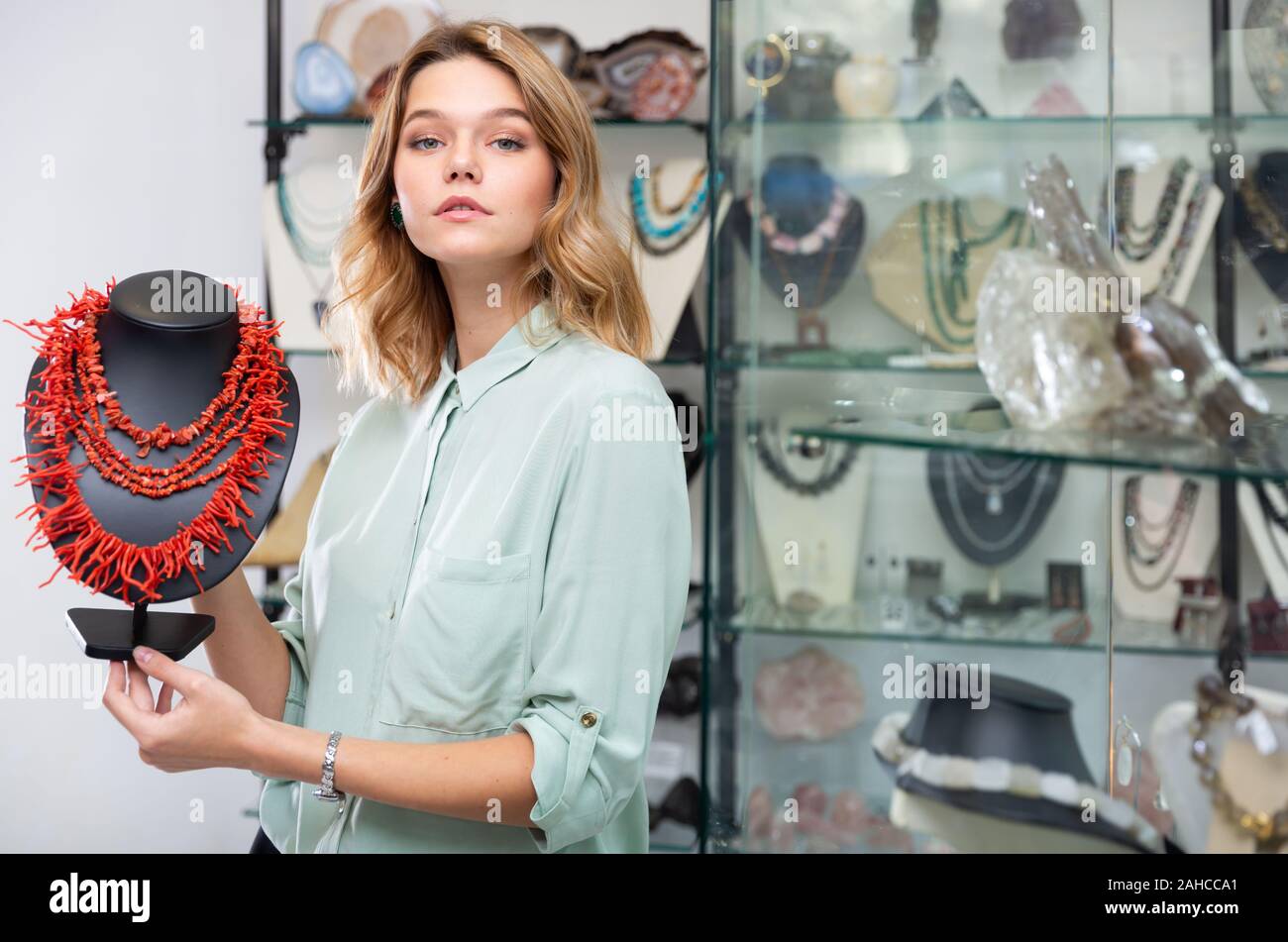 Erfolgreiche junge Verkäuferin zeigt rote Koralle Kette Schmuck Shop  Stockfotografie - Alamy