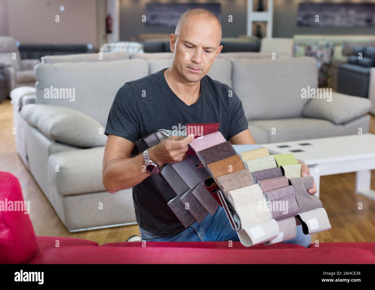 Männliche Kunden die Wahl der sitzbezüge Stoff aus dem Katalog mit Proben in einem Möbelgeschäft Stockfoto