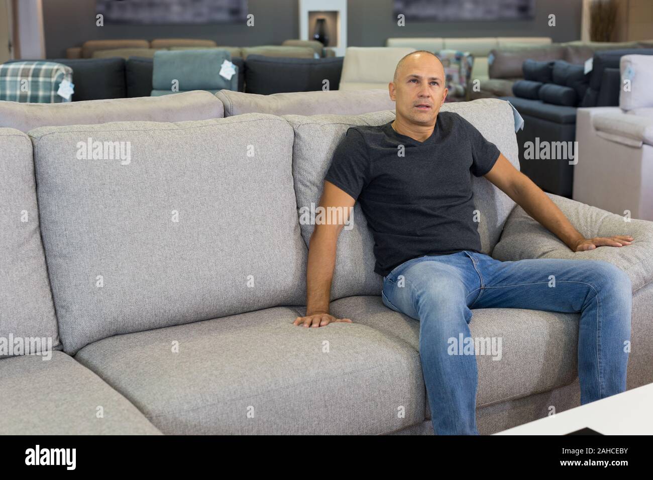 Portrait von positiver Mann testen Hellgrau Sofa im Möbel Shop Stockfoto