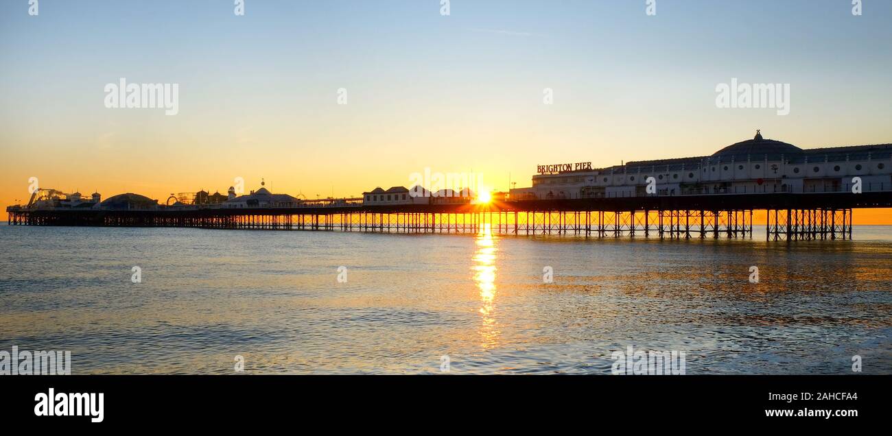 Brighton Pier, Stretching Meer bei Sonnenuntergang, die Front der Pier mit dem Namen auf, die Sonne unter der Pier bilden einen schönen Stern b Stockfoto