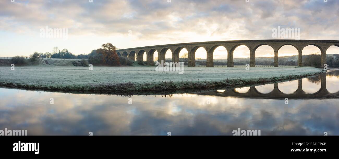 Die Bögen des Arthington Viadukt im unteren Wharfedale, Yorkshire, sind in den ruhigen Wassern des Flusses Wharfe an einem frostigen Herbst morgen wider. Stockfoto
