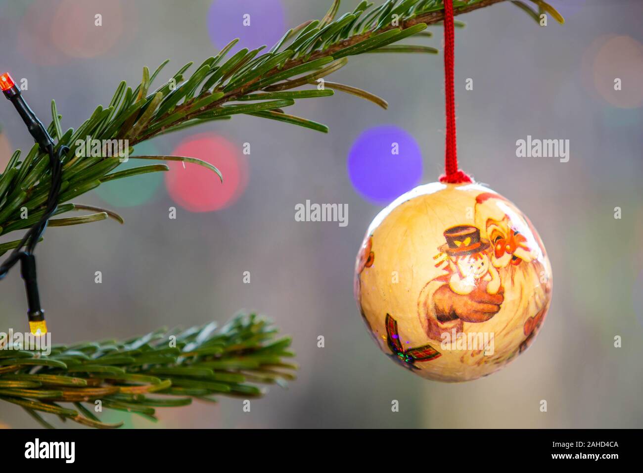 Hand-made Christbaumkugel hängt am Ast eines Weihnachtsbaum mit unscharf Lichterketten in den Hintergrund Stockfoto