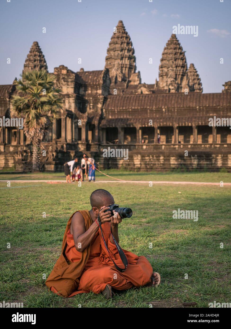 Buddhistischer Mönch in traditioneller orangefarbener Robe, der Fotos vor dem Tempel von Angkor Wat, Siem Reap, Kambodscha aufgenommen hat Stockfoto