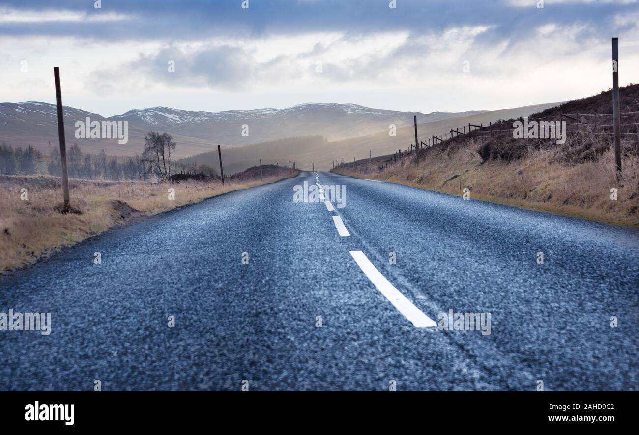 Road Trip in Schottland - schwarz Asphaltstraße mit Bergen und Mooren im Hintergrund Stockfoto