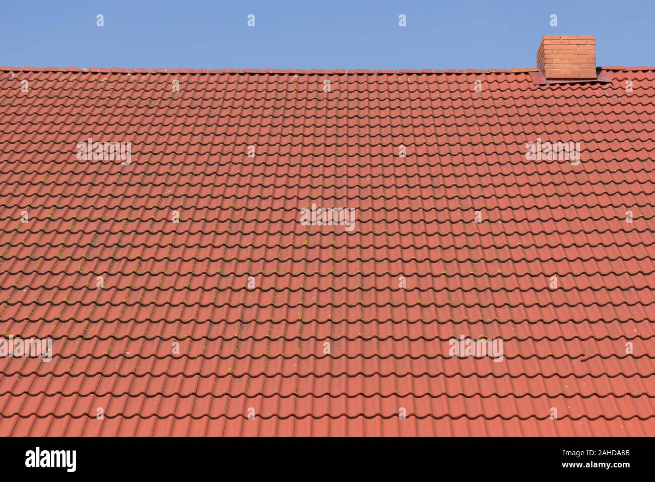 Rotes Ziegeldach mit Kamin gegen den blauen Himmel Stockfoto