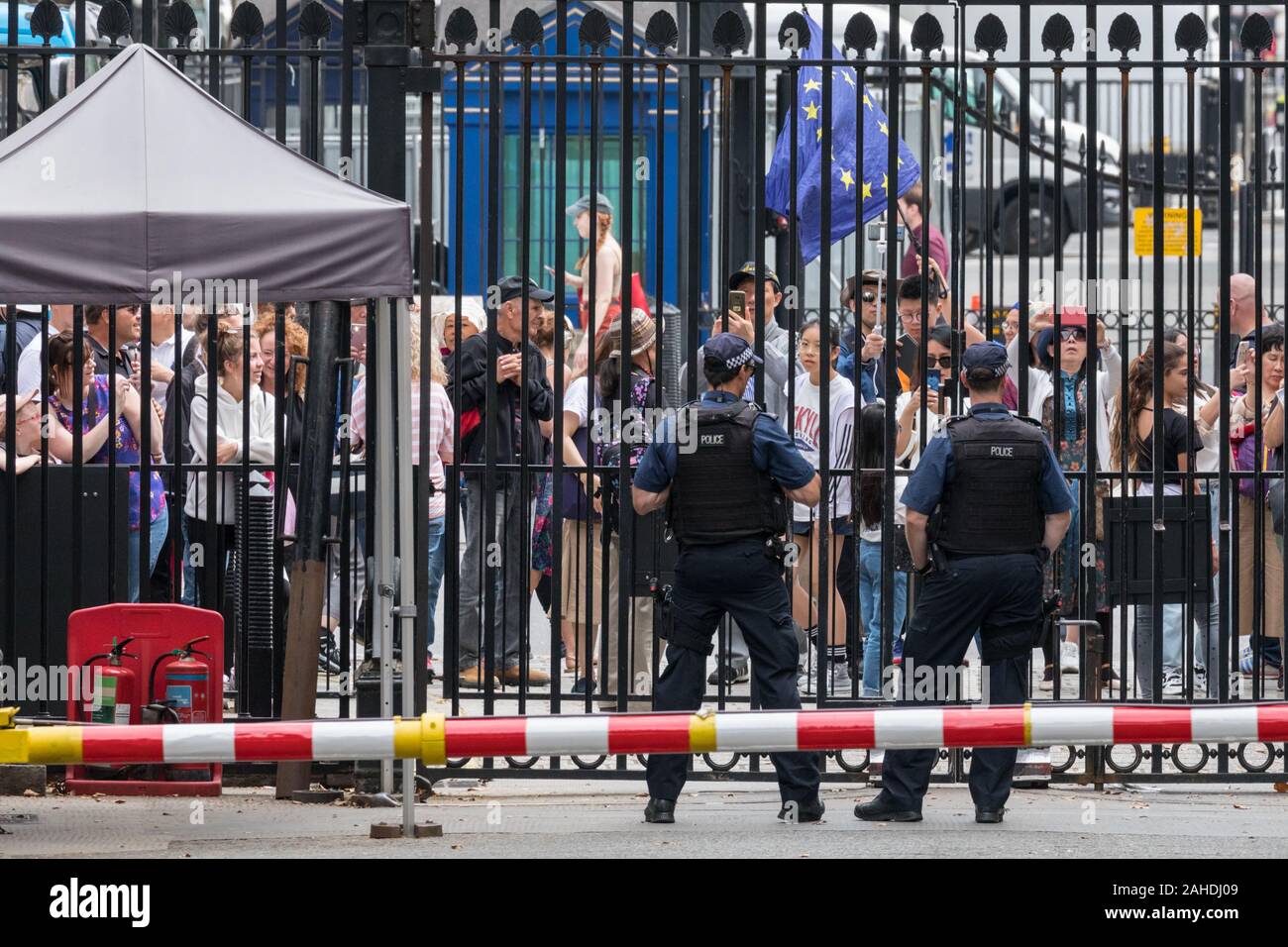 Touristen und Besucher, von bewaffneten Polizisten vor den Toren beobachtet, Downing Street, Westminster, London, UK Stockfoto