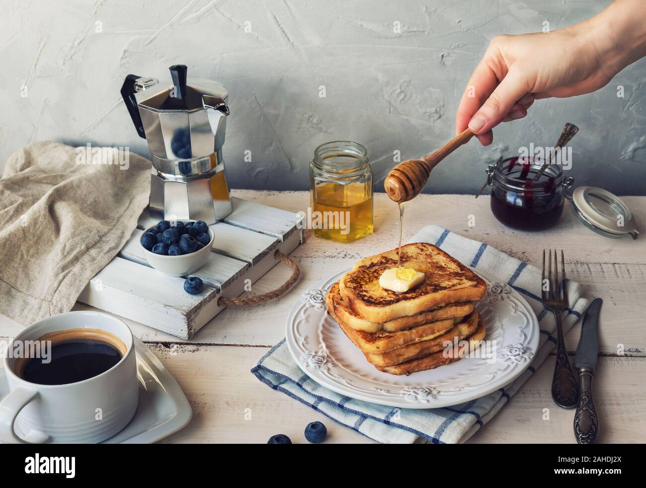 French Toast mit Butter und Heidelbeeren zum Frühstück. Hand gießt Honig auf der Oberseite. Stockfoto