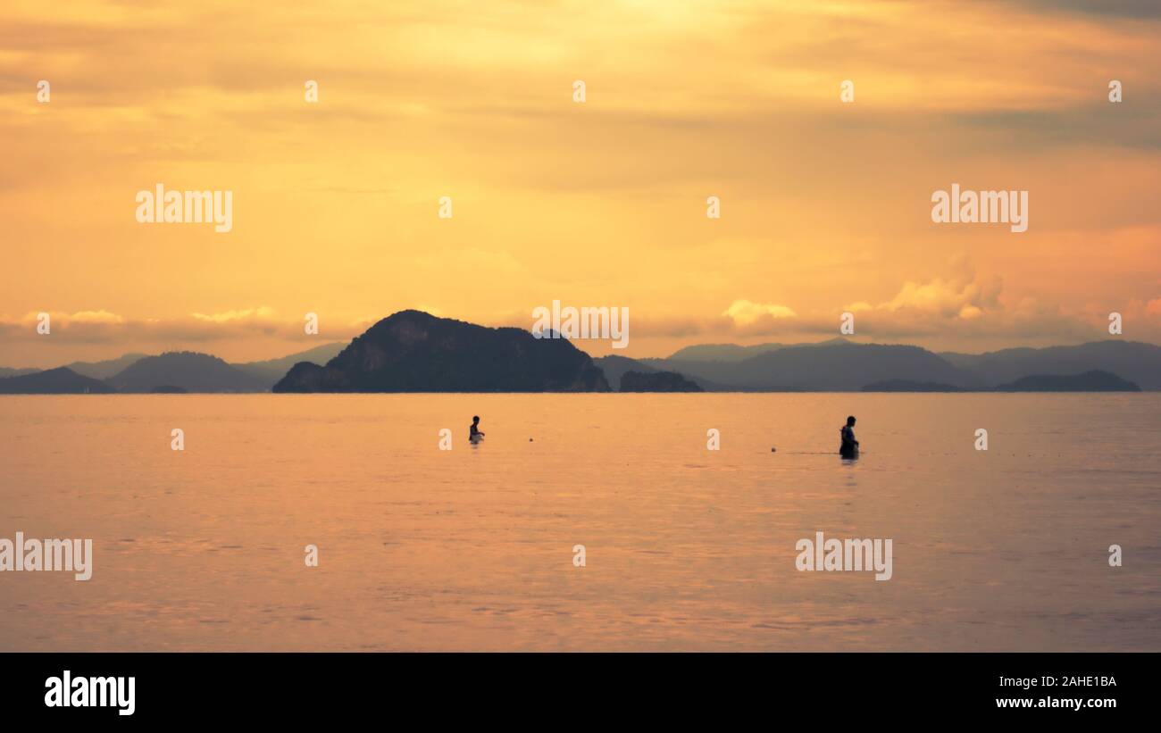Zwei Fischer bei Sonnenuntergang sammeln ihren Fang in Yao Yai Island, Thailand. Stockfoto