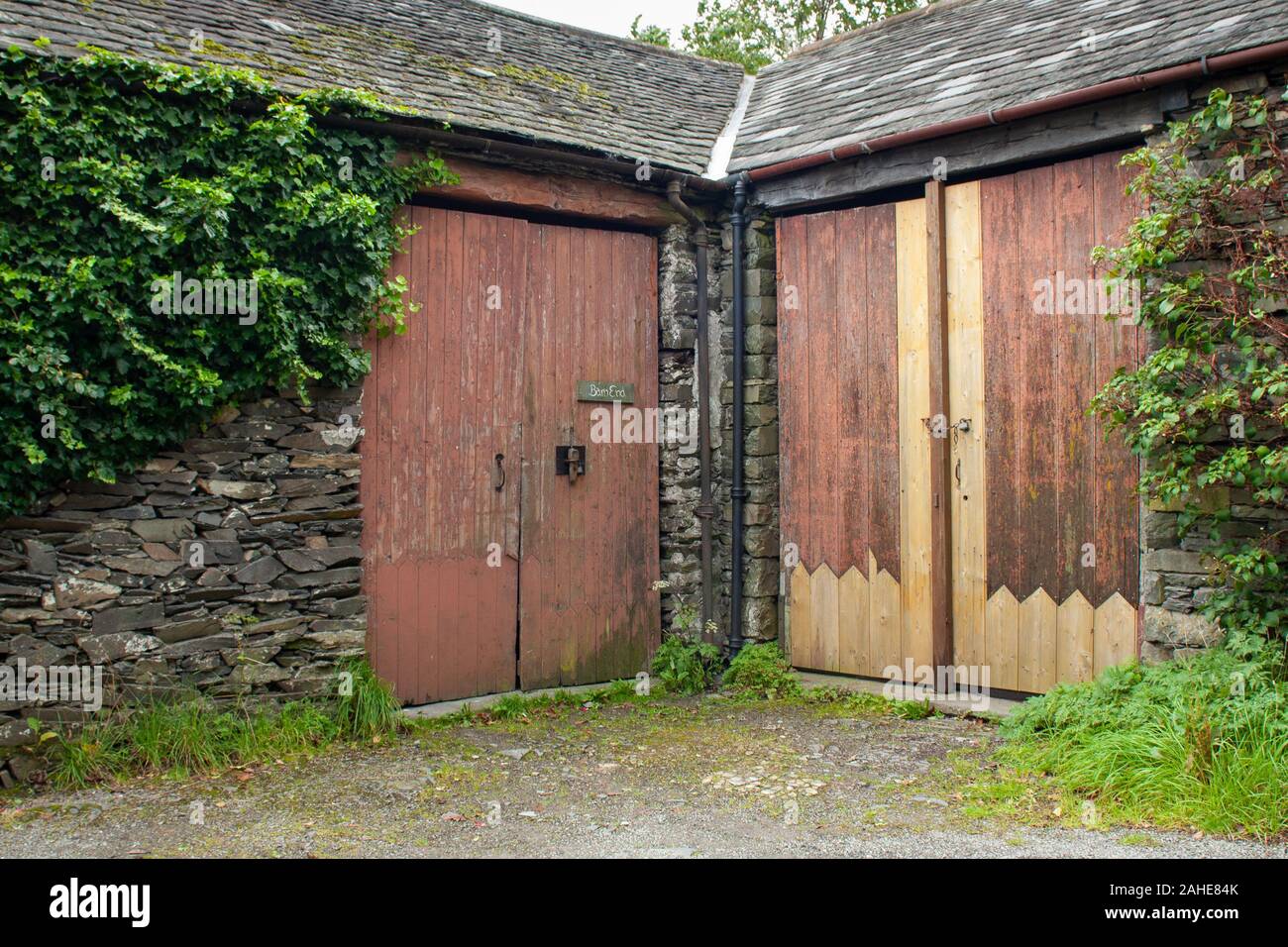 Braune Holztüren einer Steinscheune auf einem Bauernhof in Lake District, Großbritannien Stockfoto