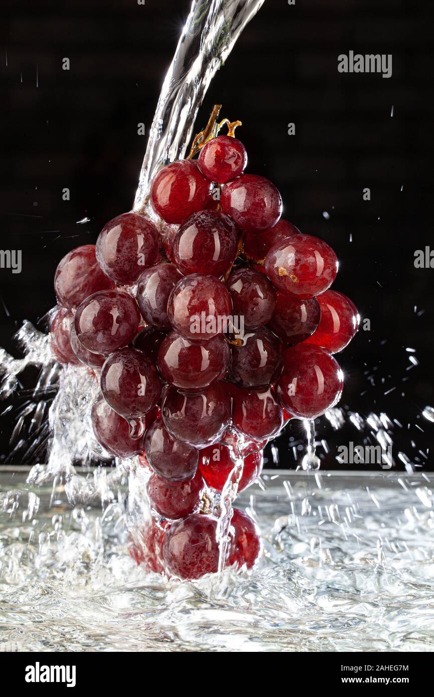 Weintraube und Strom von Wasser auf ein Studio Hintergrund Stockfoto