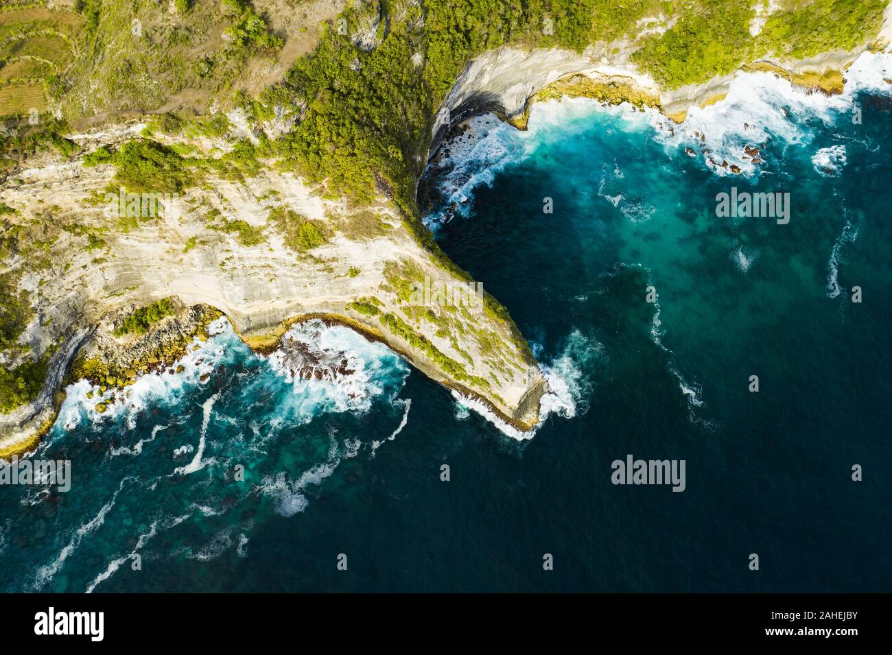 Ansicht von oben, beeindruckende Luftaufnahme von Grünem Kalkstein vom türkisfarbenen Meer bei Sonnenuntergang getaucht. Nusa Penida, Indonesien. Stockfoto