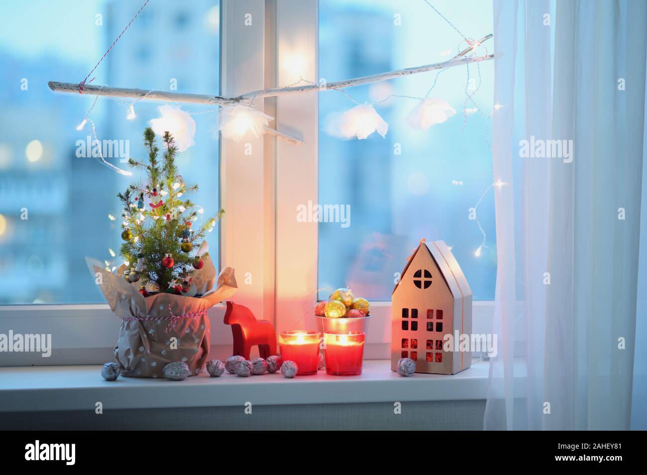 Weihnachtsbaum, Weihnachtsschmuck, Kerzen und Weihnachten Geschenk auf dem Fensterbrett Stockfoto