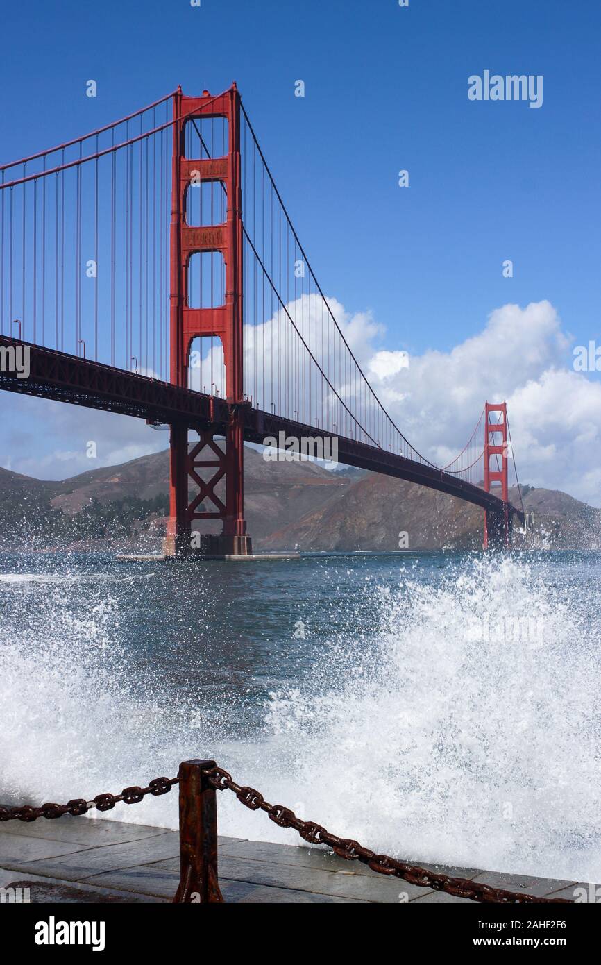 Internationale orange Golden Gate Bridge mit Wellen brechen sich an der Böschung vorne in San Francisco, Vereinigte Staaten von Amerika Stockfoto